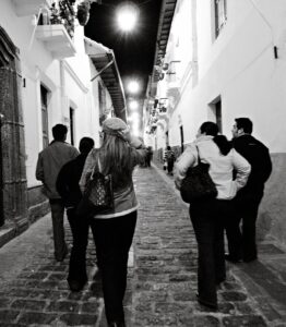 Group of people walking down a charming cobblestone street in Quito at night.